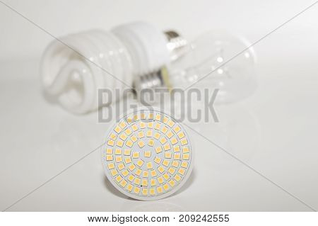 Several different led bulbs and compact fluorescent lamps with the size of the male screw base E27 on a light background