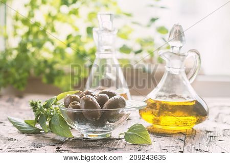 olive oil in glass bottle and olives over old wooden table