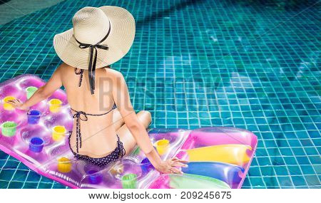 Women wearing bigini or swimware suits swimming pool sitting on a blue protrude at the resort town of Pattaya in Thailand.