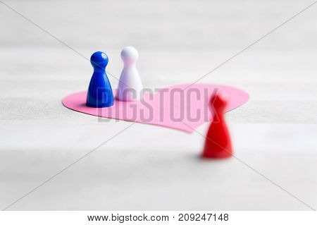 Love triangle or being third wheel. Having affair, infidelity or cheating concept. Board game pawns and paper heart on table.
