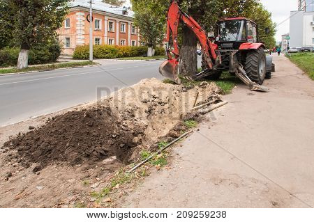 Repair Work With A Tractor On The Ruined Sidewalk In The Street