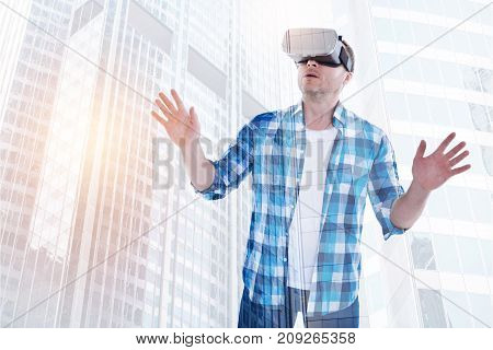 Drastic plot changes. Middle-aged bristled man playing a VR game and wearing a VR headset while spreading his hands and recoiling because of a sudden plot change