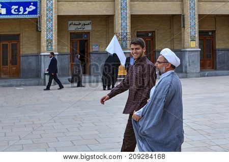 Fars Province Shiraz Iran - 19 april 2017: Shah Cheragh Shrine A Muslim clergyman passes through the courtyard of the mosque together with his young subordinate.