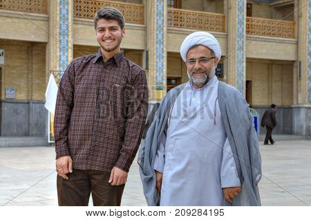 Fars Province Shiraz Iran - 19 april 2017: Shah Cheragh Shrine An elderly Muslim cleric in a white turban and his young companion posing for a photographer in the courtyard of the mosque.