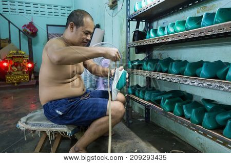 BANGKOK, THAILAND, SEPTEMBER 23, 2016 : A man is working in a local little shoes factory in the Talat Phlu district in Bangkok, Thailand