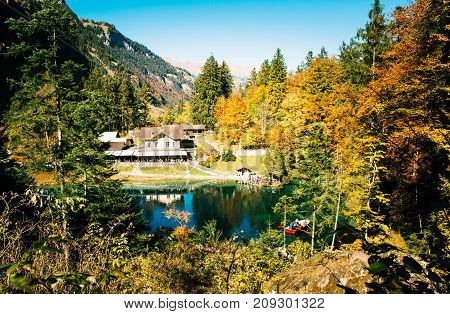 Landscape in autumn with a house and sunlight shining through the trees.