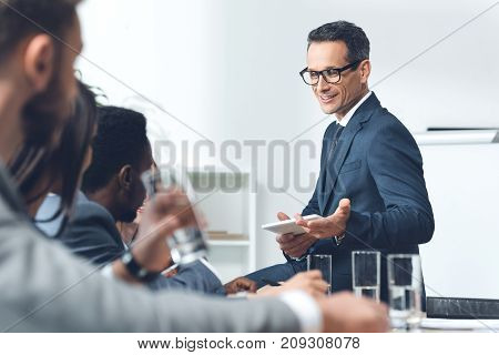 handsome middle aged businessman talking to parters at conference hall