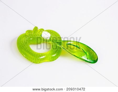 baby teeth care. green composition of toothbrush and teether on white background