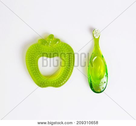 baby teeth care. green composition of toothbrush and teether on white background