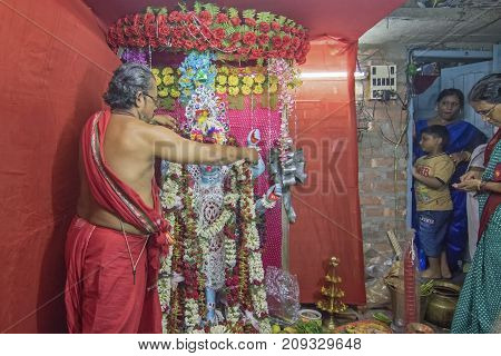 KOLKATA INDIA - JUNE 17 2017 - Hindu priest worshipping Goddess Kali at night during Kali Puja Hindu festival of Deepavali or Diwali. Celebtated all over India. Shot under mixed light.