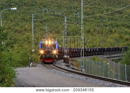 ABISKO, SWEDEN ON SEPTEMBER 03. View of an Electrical Ore Line Train in speed loaded with iron ore comes in on September 03, 2009 in Abisko, Sweden. Autumn, and lights on. Editorial use.