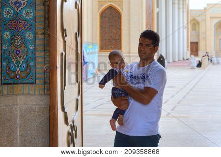 Fars Province Shiraz Iran - 19 april 2017: Shah Cheragh Shrine Muslim man with a small child in her arms pass through the large gate of mosque.
