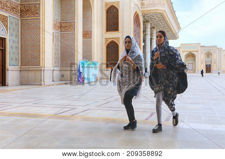 Fars Province Shiraz Iran - 19 april 2017: Shah Cheragh Shrine Two fashionable young Iranian women pass through the inner courtyard of the mosque.