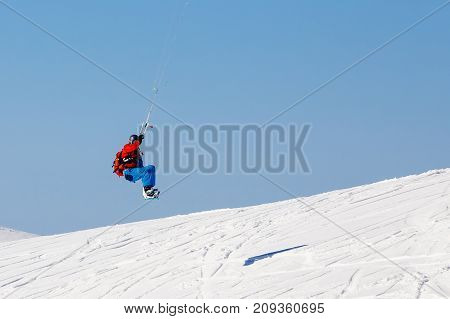 Snowboarder with a kite on fresh snow in the winter in the tundra of Russia against a clear blue sky. Teriberka, Kola Peninsula, Russia. Concept of winter sports snowkite.