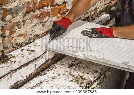 Construction worker thermally insulating house foundation walls with Styrofoam boards