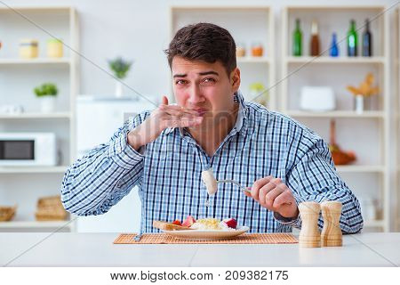 Man eating tasteless food at home for lunch