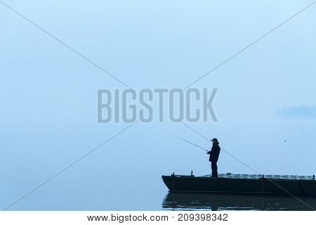 BELGRADE SERBIA - JANUARY 18 2015: Fisherman fishing on the Danube river during a heavily foggy winter afternoon in Zemun a northern district of Belgrade