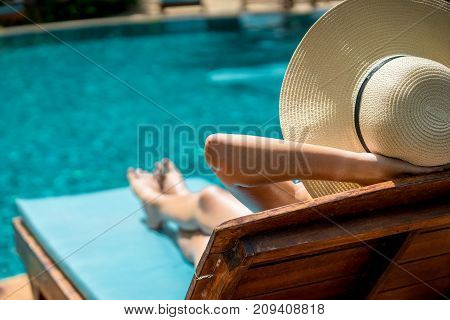 Women wearing bikini or swimware suits at swimming pool relax on the pool bed at the resort of Pattaya in Thailand.