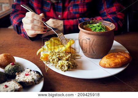 Woman eating beans at clay pot and vegetarian snakes pkhali Georgian cuisine at restaurant in Tbilisi Georgia