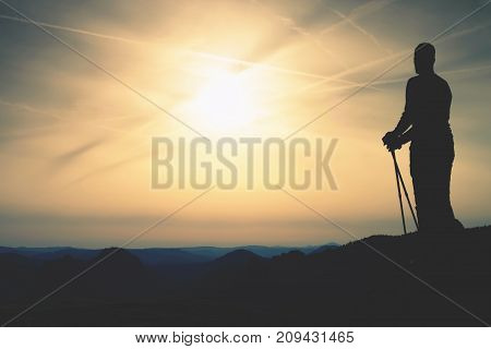 Silhouette Of Tourist With Poles In Hand. Sunny Spring Daybreak
