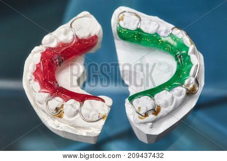Colorful dental braces or retainers for teeth on black glass background closeup