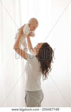 Cheerful woman playing with adorable infant child.