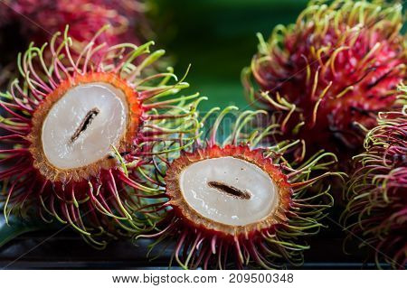Fresh rambutan fruit and cross section showing the thick red skin and white flesh, Delicious rambutan sweet fruit , closeup, fruit in Asia