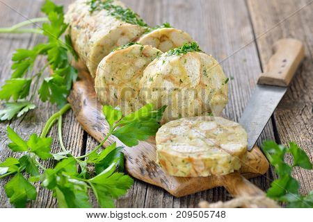 Sliced Bavarian bread dumpling ,  the perfect side dish for roasts or strips of meat with sauce,  served on a wooden cutting board