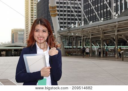 Portrait of successful young Asian business woman standing and looking confident against urban background.