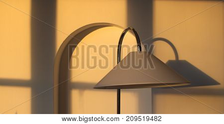 Lamp with linear shadows and arch in the wall.