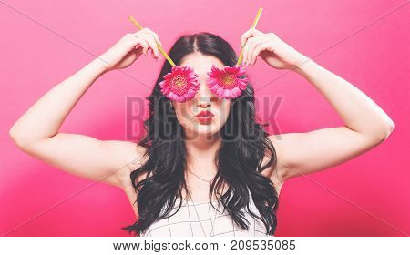 Young woman with garbera on a solid background
