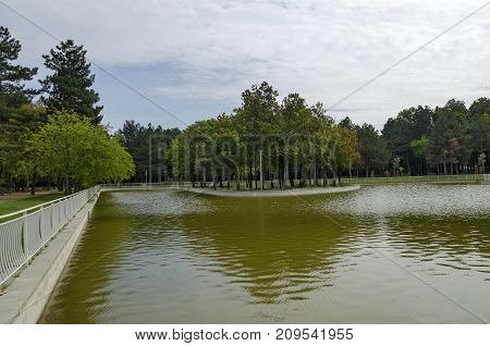 Popular  North park  for rest with autumnal old forest, wooden bench and lake in  Vrabnitsa district, Sofia, Bulgaria