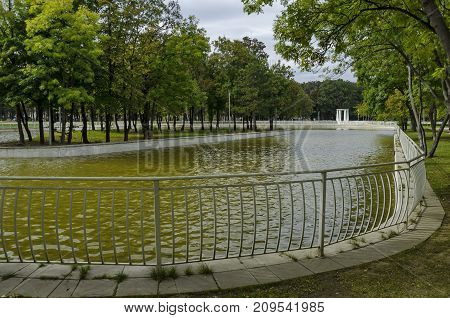 Popular  North park  for rest with autumnal old forest, wooden bench and lake in  Vrabnitsa district, Sofia, Bulgaria