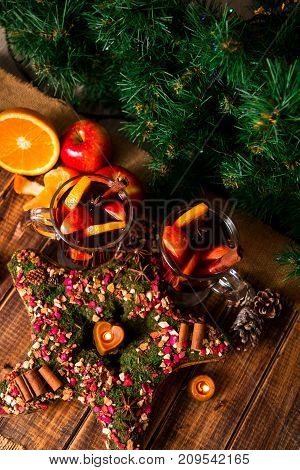 Christmas star near mulled wine with fruits and spices on wooden table. Xmas decorations in background. Two glasses. Winter warming drink with recipe ingredients around. top view