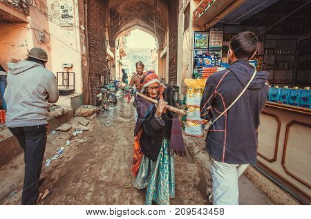 SHEKHAWATI, INDIA - FEB 6, 2017: Older woman shopping and crowd of walking people on historical indian street on February 6, 2017. With richly decorated palaces Shekhawati is famous area of Rajasthan