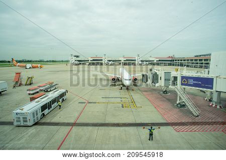 BANGKOK THAILAND  21 JULY 2017: Ground crew directing an incoming airplane into position to meet a jet-way bridge in Don Mueang international airport (DMK)