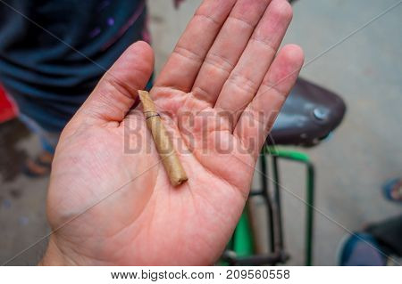 Delhi, India - September 25, 2017: Close up of a hand of a man with a leaf wrapped cigarette handmade, in the streets of Paharganj new delhi India.