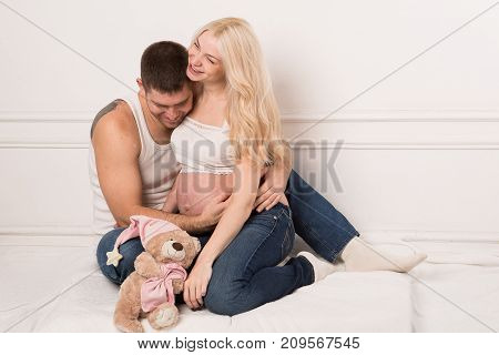 Beautiful pregnant couple in love on the background. Hands of husband on the tummy of his pregnant wife. Young man tenderly stroked pregnant belly of his wife. Husband kissing pregnant belly.