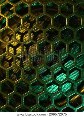 full frame colourful illuminated detail of a metallic grid in front of a loudspeaker
