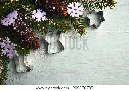 Christmas decoration.Decorative snowflakes,fir cones and snowy fir tree branch on light blue wooden background with copyspace.Winter holidays,Merry Christmas or Happy New Year concept.Selective focus.