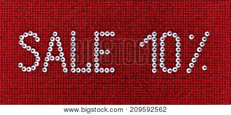 Word SALE is made rhinestones crystal color on a red canvas background