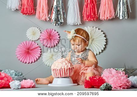 Little baby girl eating birthday cake during cake smash party