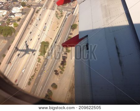 Hey stark shadow tags along a landing 747 as it lands in a metropolitan international airport.
