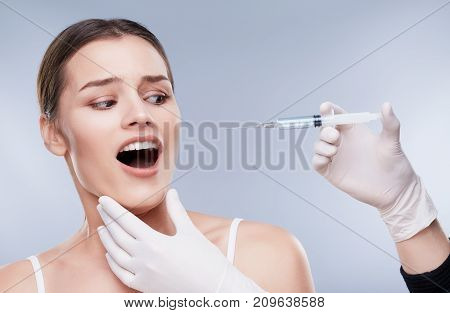 Scared Patient Of Dentist Looking At Syringe