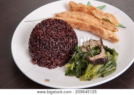 Vegetarian food Thai-style with Stir-fried vegetables spinac and shiitake Riceberry rice tamarind paste and sour soup (Selective Focus Focus on the Riceberry rice)