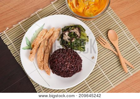 Vegetarian food Thai-style with Stir-fried vegetables spinac and shiitake Riceberry rice tamarind paste and sour soup (Selective Focus Focus on the Riceberry rice)