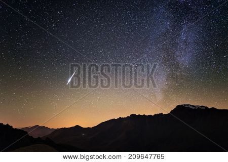 Milky Way and starry sky from high up on the Alps. Real Christmas comet in the sky. Majestic high mountain range with glacier and snow.