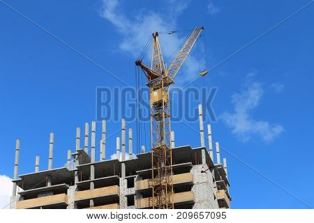 Big yellow stationary hoist on construction site part of building blue sky and white clouds