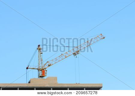 Big yellow stationary hoist on construction site part of building blue sky