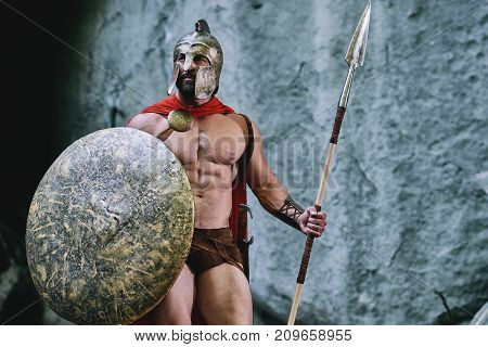 Spartan warrior with perfect muscular body looking away posing armored ready for battle copyspace.